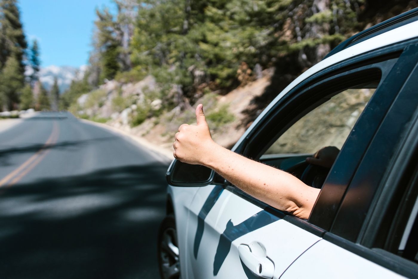 person-driving-car-giving-thumbs-up