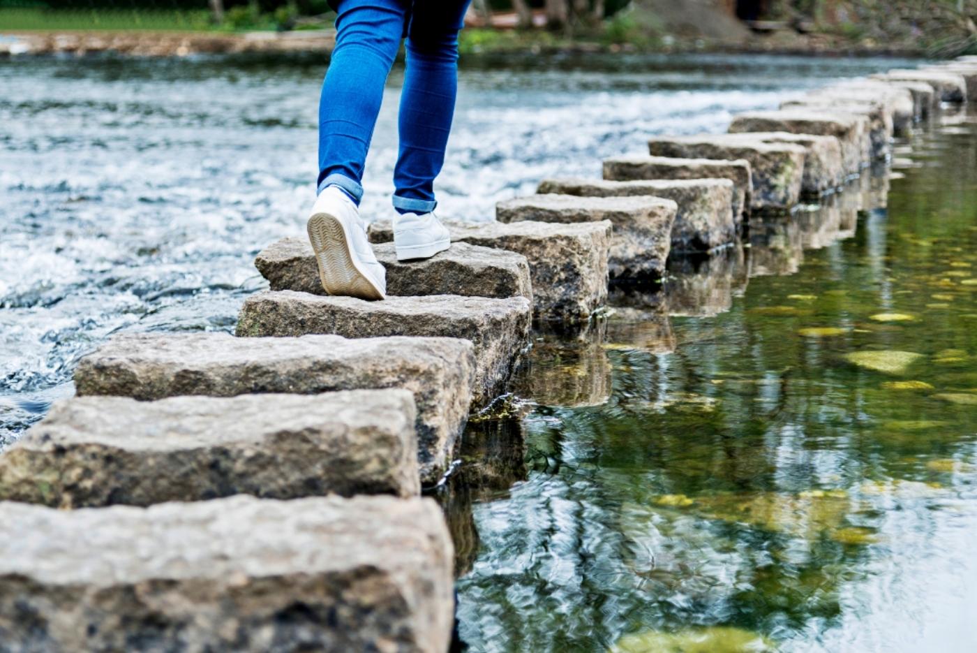 Woman walking across stones Woman walking across stones