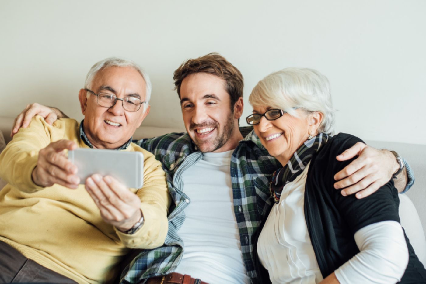 Man taking a selfie with his smiling parents on the couch